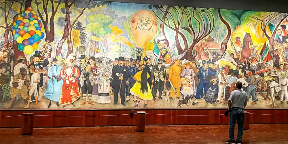 Visitor viewing a Diego Rivera mural at Palacio de Bellas Artes